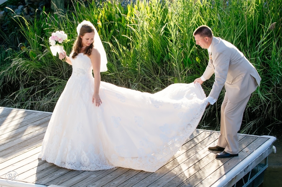 groom fluffs the brides wedding dress
