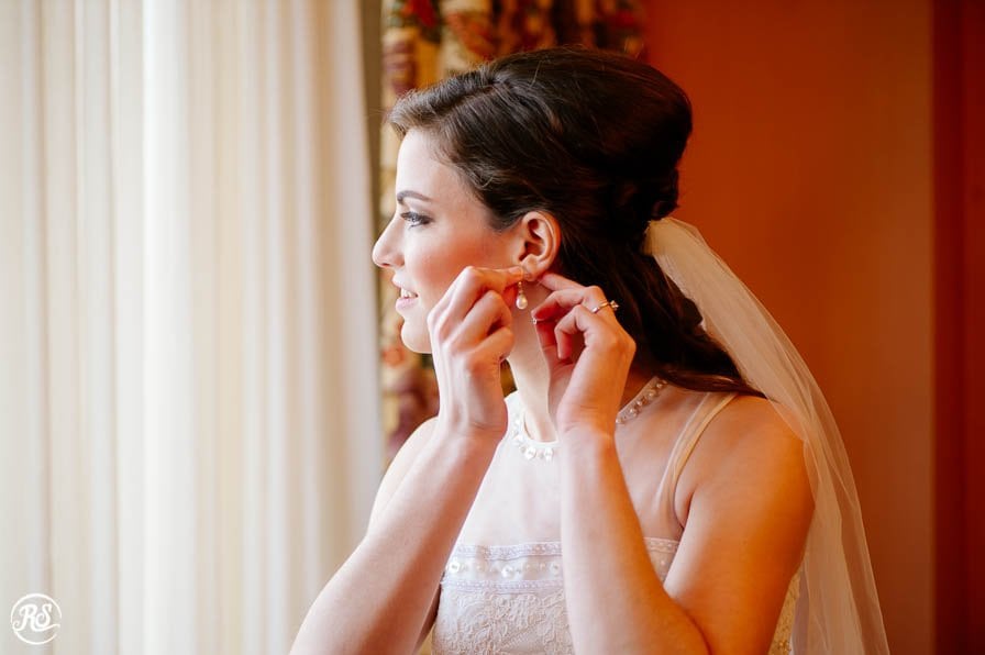 bride putting on wedding day earrings 