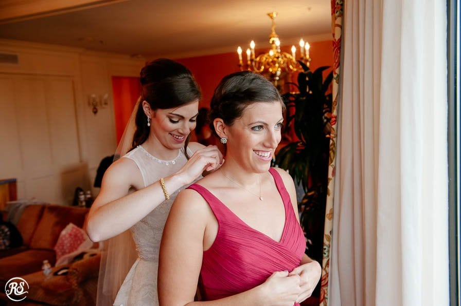Bride helping maid of honor getting ready for wedding