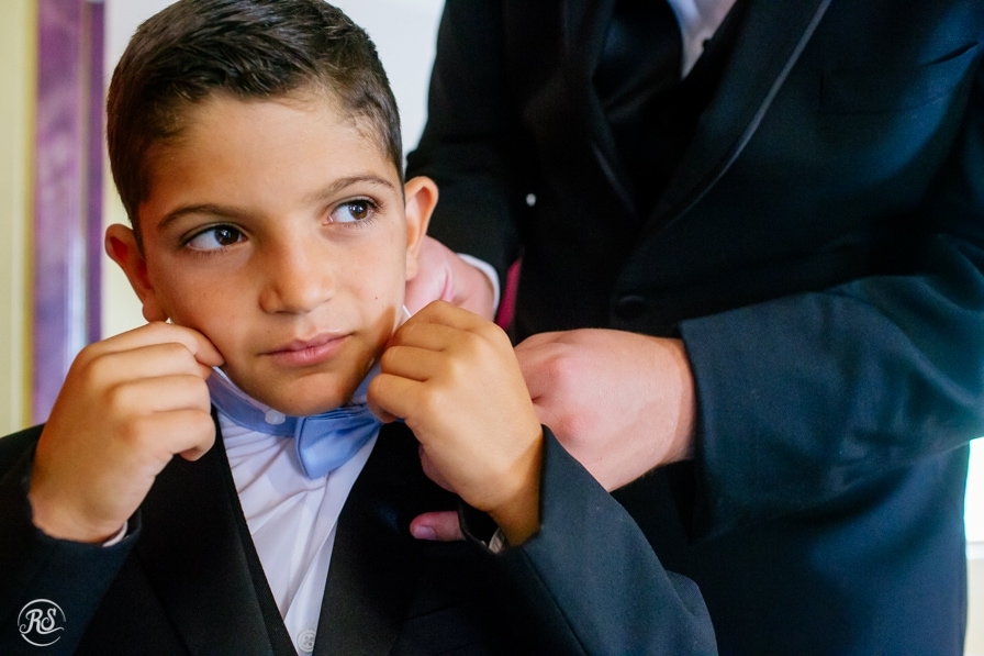ring bearer putting on bow tie