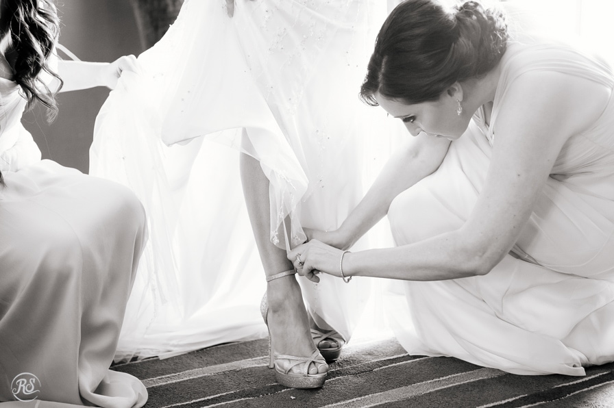 Maid of honor putting on brides shoes 
