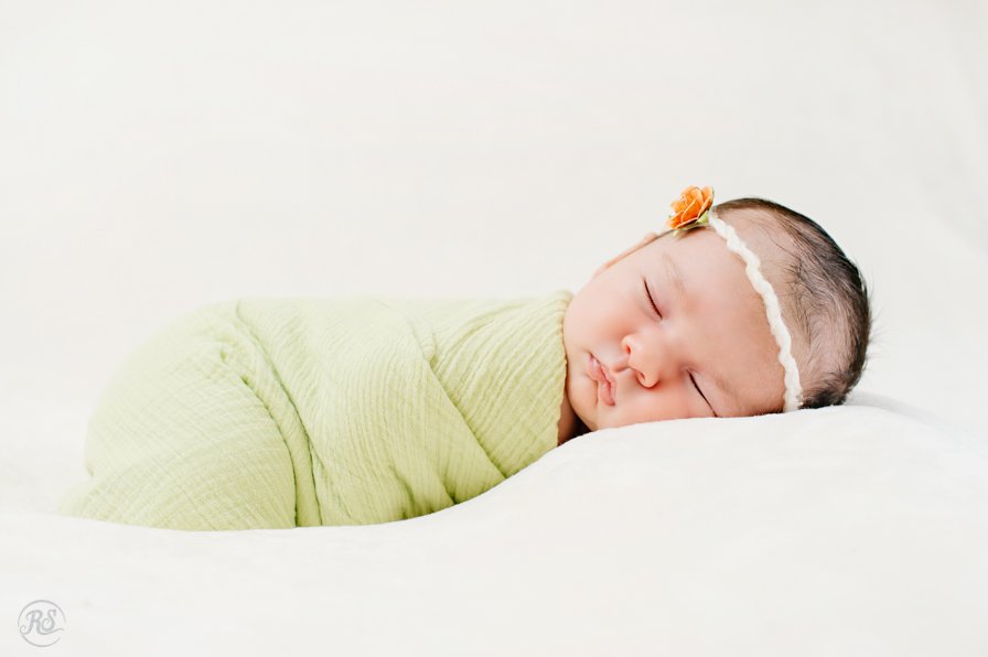 sleeping baby in green swaddle