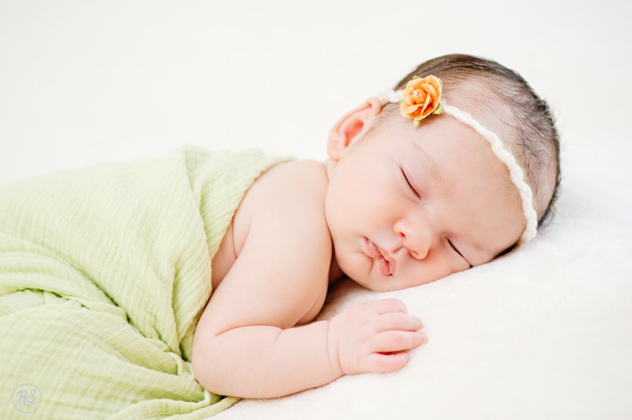 Sleeping baby girl with green wrap and peach hairband