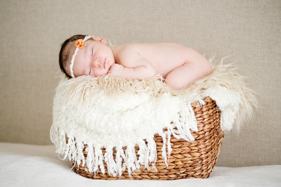 baby in basket with white blankets and furs