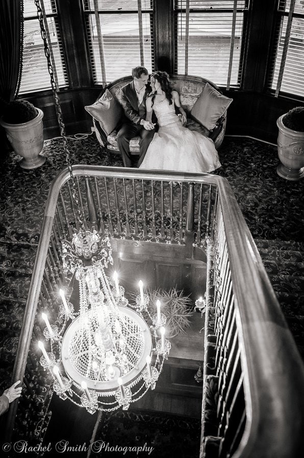 Black and white photo of bride and groom under chandelier 