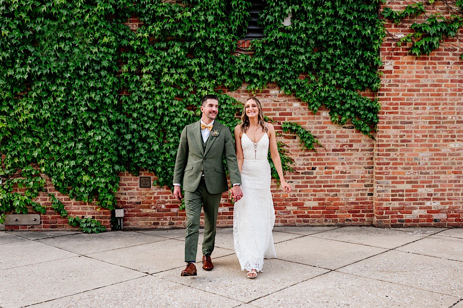 bride and groom candid walking photos with ivy wall backdrop