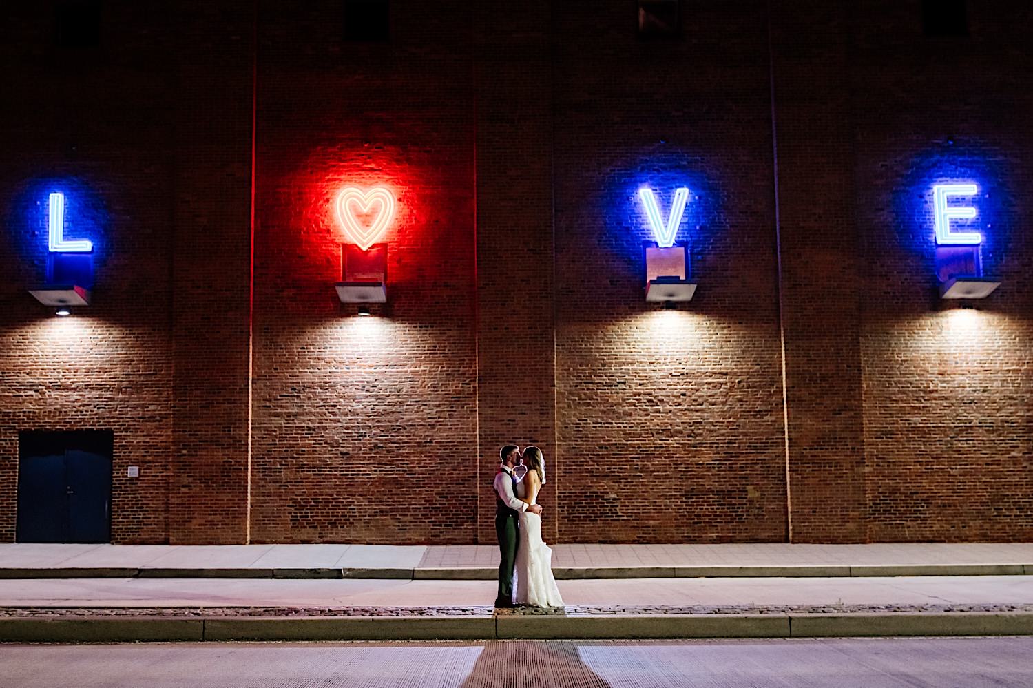 night time wedding photo in front the the Baltimore American visionary art museum neon love sign