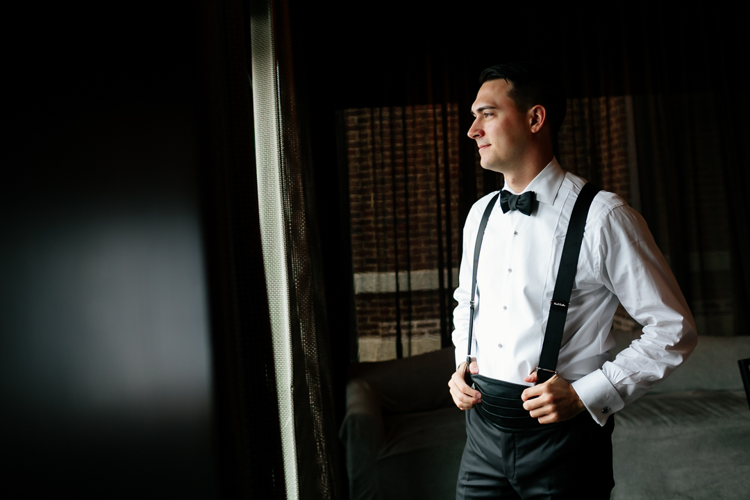 groom looking out window during wedding prep
