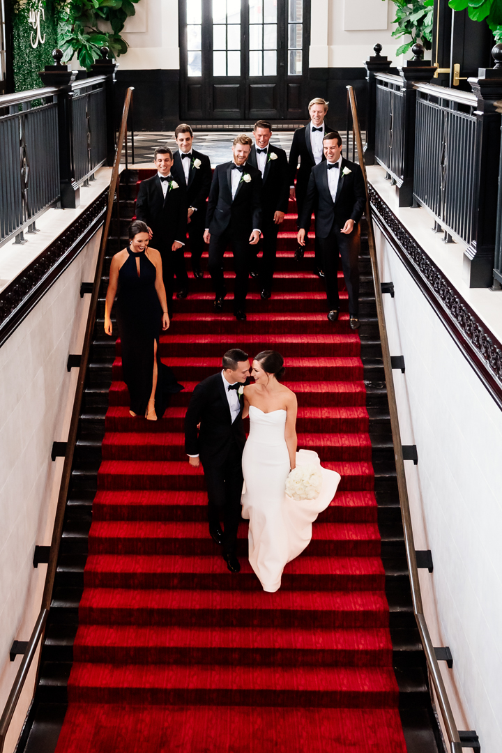 candid of bride and groom walking down stairs with wedding party