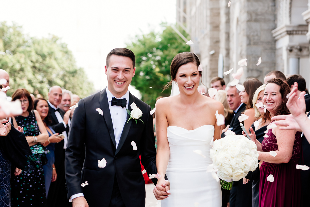 guests throw rose petals at newlyweds as they exit holy rosary church