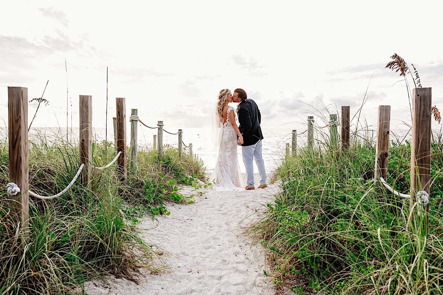 bride and groom kissing on beach dune